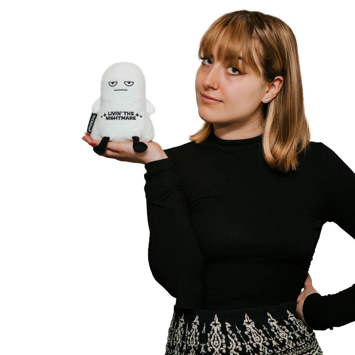 Woman with bangs holding the Livin’ the Nightmare ghost plush in her palm to show its small size
