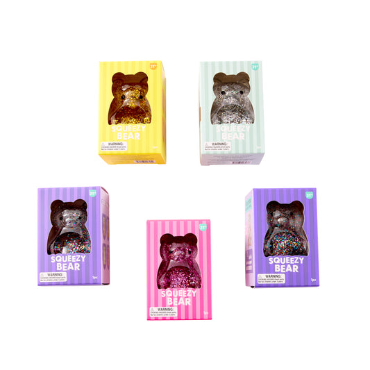 Assorted boxed J'adore Squeezy Bear glitter squishy toys in pink, yellow, silver, and multicolor.