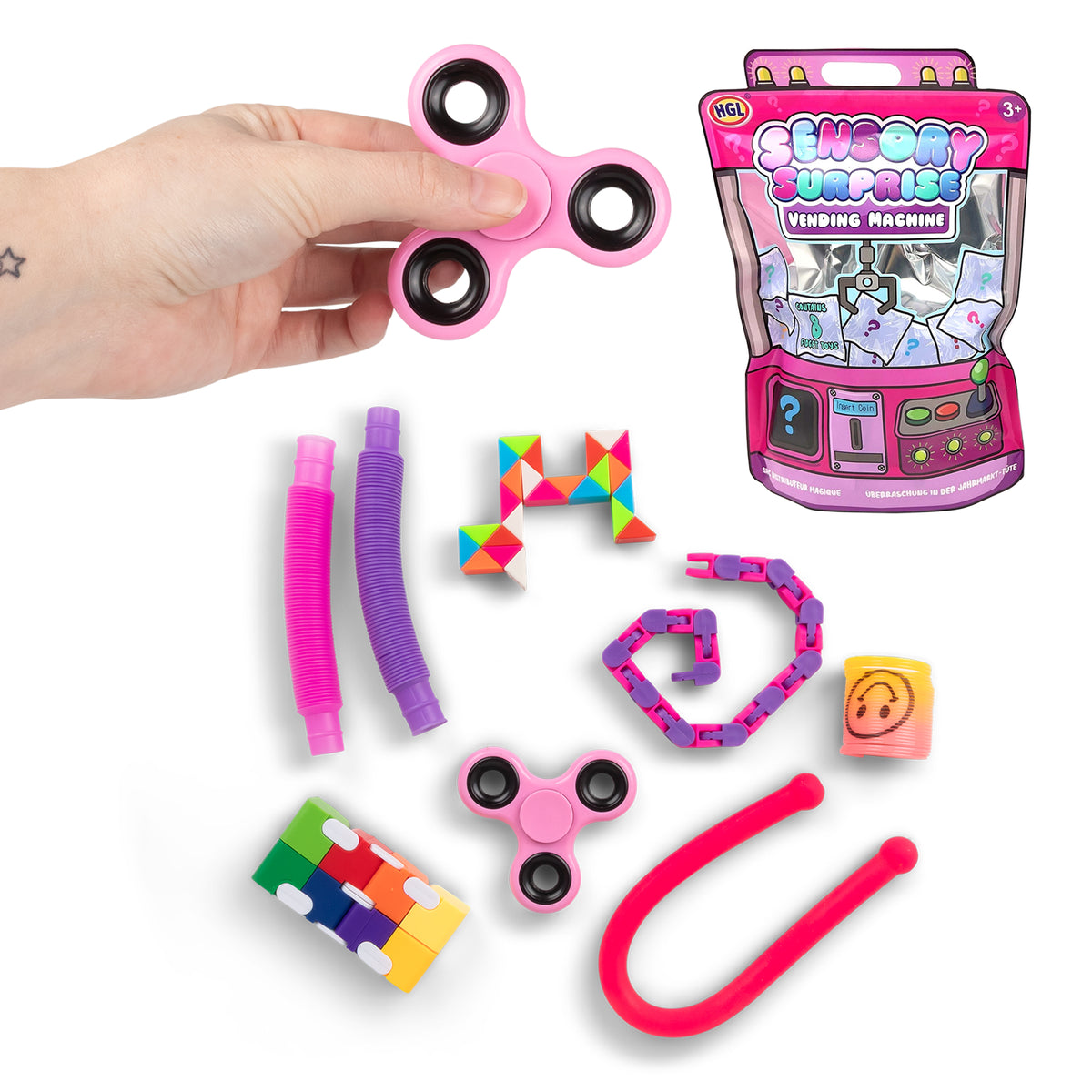 Sensory Surprise Vending Machine mystery bag contents laid out: fidget spinners, pop tubes, snake puzzle, wacky track chain, and slinky, with retail packaging