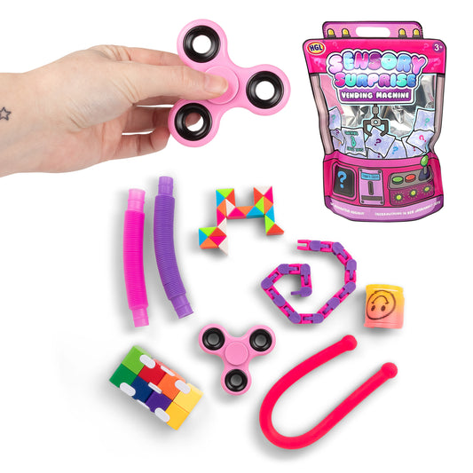 Sensory Surprise Vending Machine mystery bag contents laid out: fidget spinners, pop tubes, snake puzzle, wacky track chain, and slinky, with retail packaging