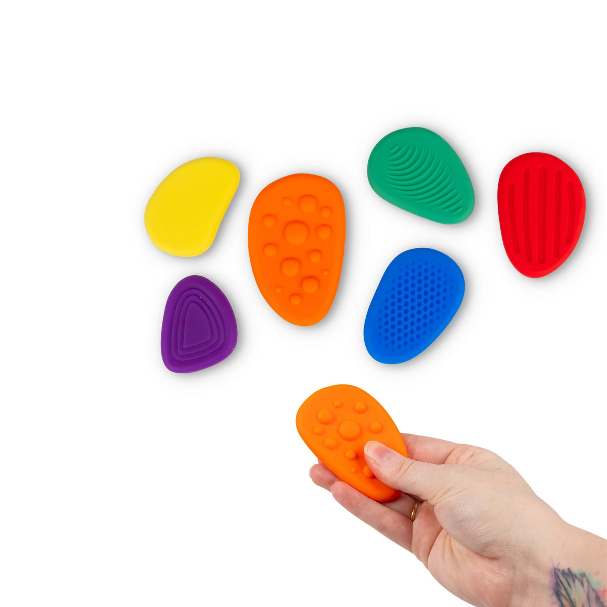 Sensory Worry Stones 6-pack flat lay with hand holding orange stone, showing all textures