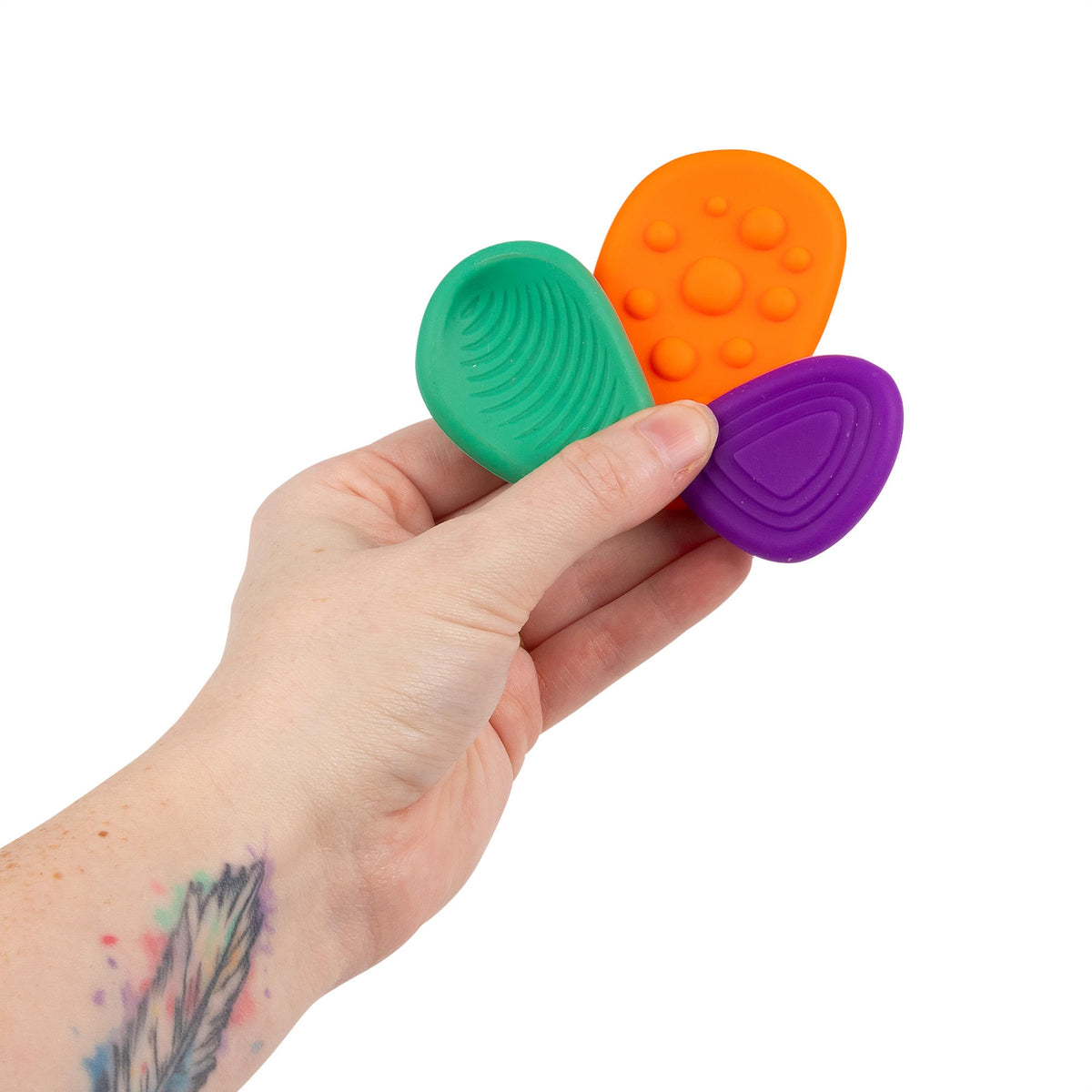 Hand holding red, blue, and yellow Sensory Worry Stones showing ridged and dotted textures