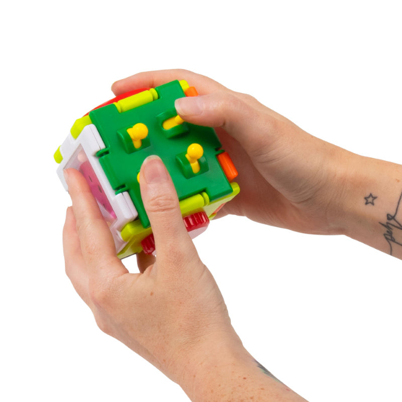 Hands pressing the green side buttons on the Super Sensory Square fidget cube