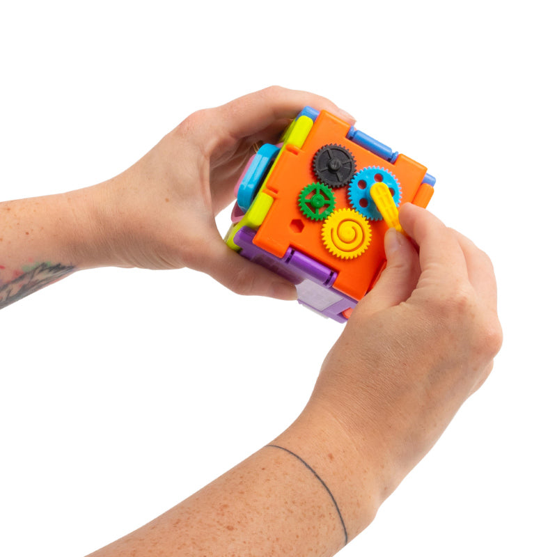 Hands spinning the gears on the orange side of the Super Sensory Square fidget cube