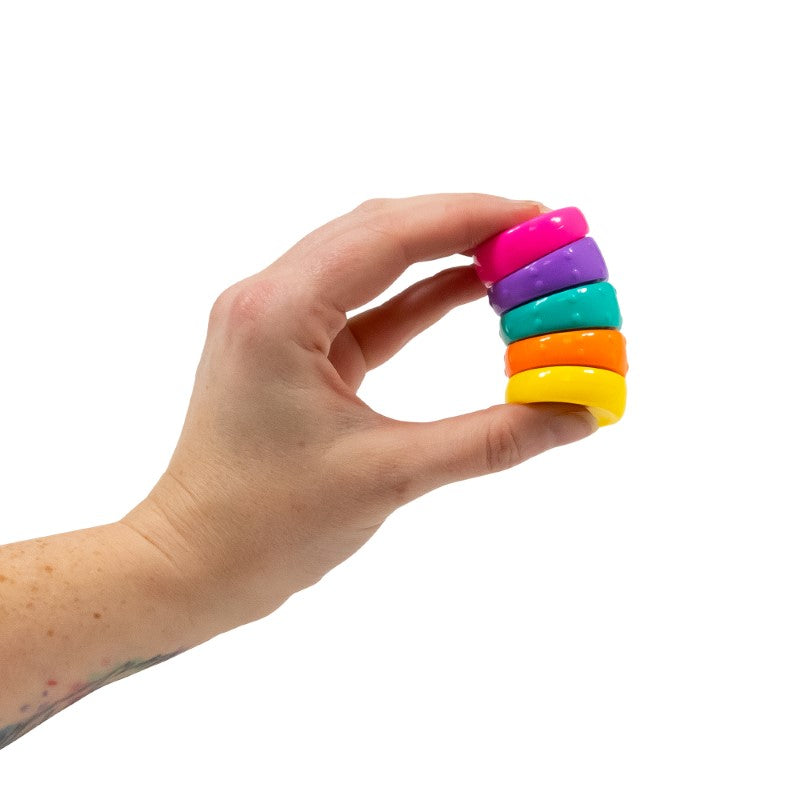 Hand holding the Torsion Rainbow Circle fidget toy from the side
